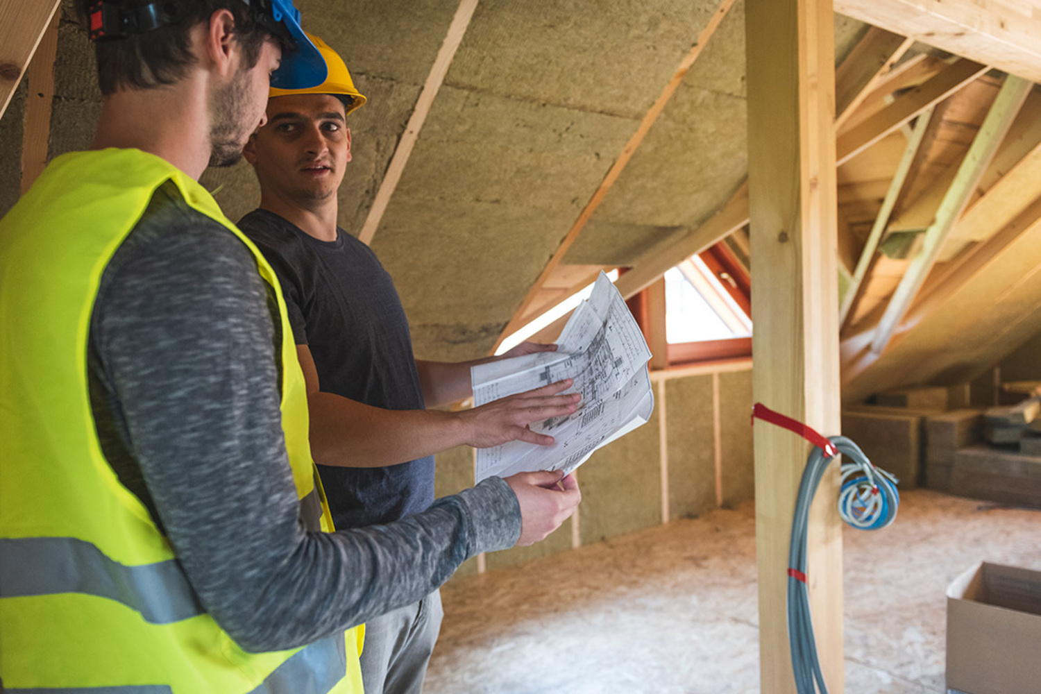 Zwei Handwerker mit Bauplan im Dachrohbau